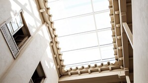 A high-ceilinged atrium with a skylight, wooden beams, and a decorative wall piece.