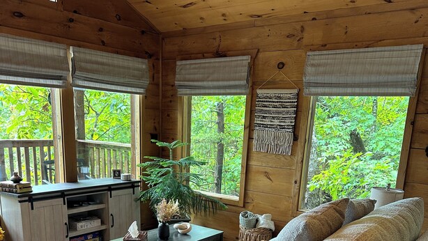 A cozy cabin interior with a wooden floor, a sofa, a coffee table, and a lamp. -  Eureka Springs Riverview Oasis: A Serene Retreat Overlooking the White River  (Eureka Springs)