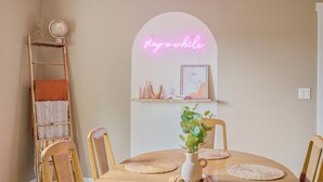 Un coin repas avec une table en bois, des chaises, un globe terrestre, un néon et une étagère ornée d’objets décoratifs.