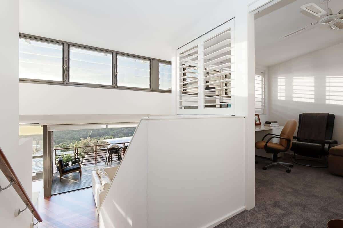 A modern interior with a balcony, office space, and a view of the outdoors.