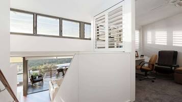 A modern interior with a balcony, office space, and a view of the outdoors.