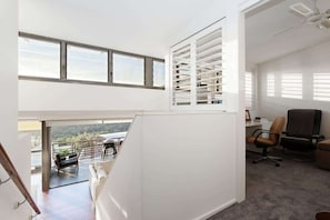 A modern interior with a balcony, office space, and a view of the outdoors.