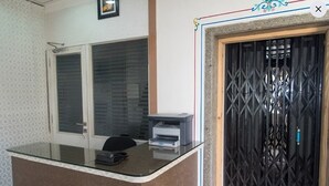 A reception desk with a glass top, a printer, and a door with a metal gate. - FabHotel Angan (Udaipur)