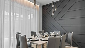 Ein moderner Essbereich mit geometrischem Wanddesign, Tisch für sechs Personen und zeitgemäßen Stühlen.