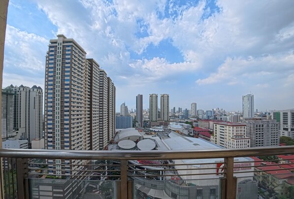 A high-rise building with multiple floors, a cityscape with various buildings in the background, and a clear sky with scattered clouds. - Yhen Airbnb Manila (Manila)