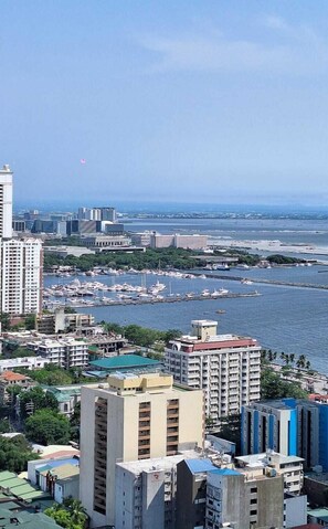 A coastal cityscape with high-rise buildings, a marina with numerous boats, and a clear view of the sea. - Yhen Airbnb Manila (Manila)
