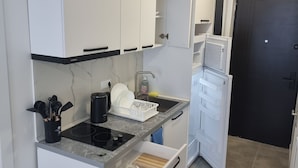 A compact kitchen with white cabinets, a built-in stove, and a refrigerator.