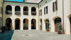 A courtyard with stone paving, arched doorways, and potted plants. - La Portesina Mantova, cozy apartment between lakes and historic center (Mantova)