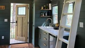 A kitchen with a wooden ceiling, a built-in sink, and a ladder. - Sagebrush Caboose (Oliver)