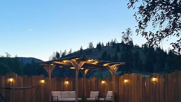 A poolside area with a wooden pergola, seating, and a wooden fence. - Sagebrush Caboose (Oliver)