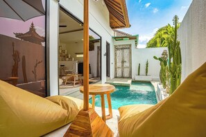 A poolside area with a wooden deck, a small table, and a chair. - Villa Orchid • 1BR • Private Pool • Central Canggu (Kecamatan Kuta Utara)