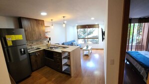 Una cocina moderna con armarios de madera, estufa integrada y un ventanal grande.