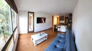 Una sala de estar moderna con un sofá, una mesa de centro y un televisor montado en la pared.