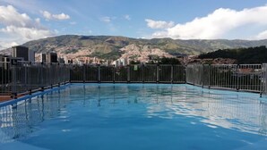 Una piscina con vistas a montañas y un paisaje urbano al fondo.