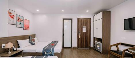 A hotel room with two beds, a desk, a chair, a TV, and a wardrobe.