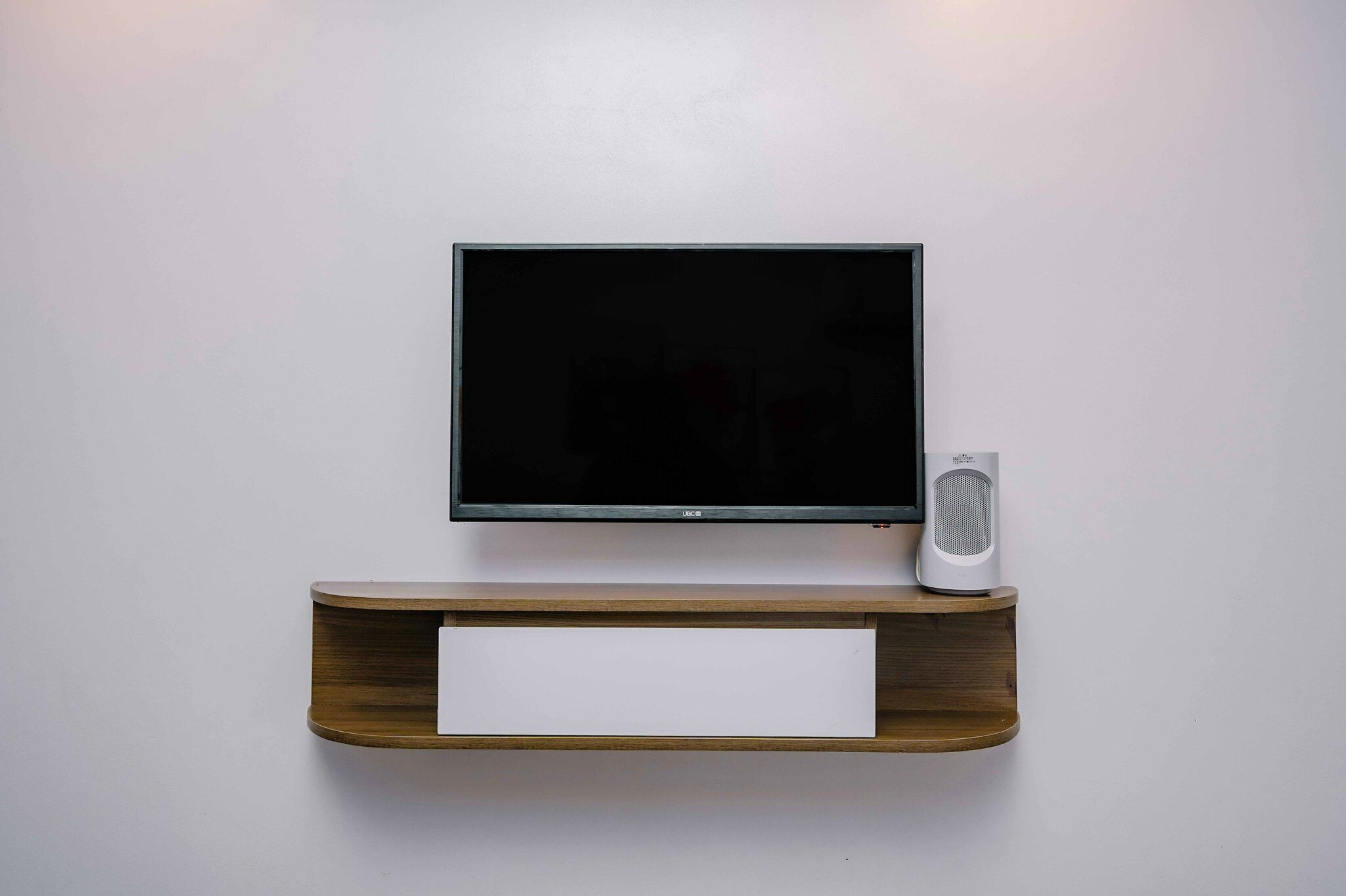 Een televisie aan een muur bevestigd, met een houten plank eronder.