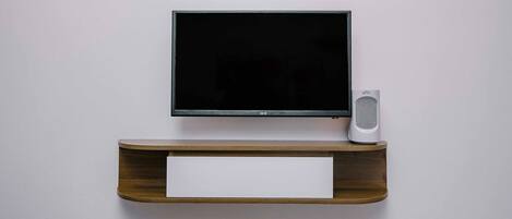 Ein an der Wand befestigter Fernseher mit einem Holzboden darunter.