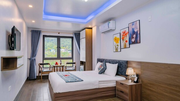 Ein modernes Hotelzimmer mit einem großen Bett, einem Nachttisch und einem an der Wand befestigten Fernseher.
