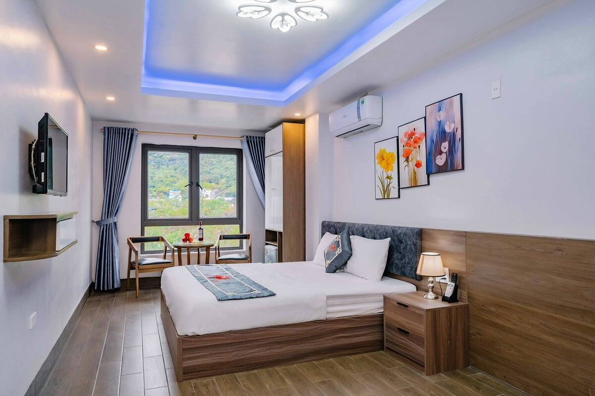 Ein modernes Hotelzimmer mit einem großen Bett, einem Nachttisch und einem an der Wand befestigten Fernseher.