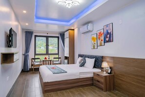 Ein modernes Hotelzimmer mit einem großen Bett, einem Nachttisch und einem an der Wand befestigten Fernseher.
