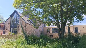 A stone building with a large glass window and a sloped roof. - 17th-Century Mill with Indoor Pool – Romantic Escape in Brittany (Ploudalmézeau)