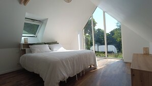 A bedroom with a large bed, a skylight, and a view of the outdoors. - 17th-Century Mill with Indoor Pool – Romantic Escape in Brittany (Ploudalmézeau)