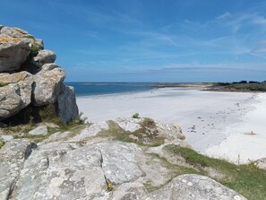 A coastal landscape with large rocks and a sandy beach.