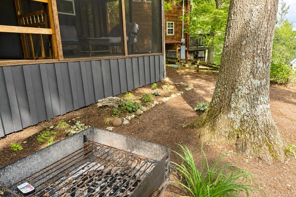Une terrasse en bois avec des meubles d’extérieur, un barbecue et un arbre.