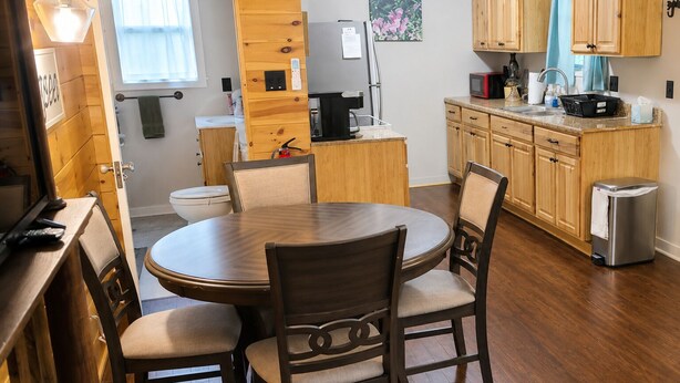 A compact kitchen with wooden cabinets, a round dining table, and a built-in oven.