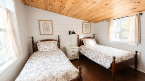 A bedroom with two wooden beds, a nightstand, and a window with curtains.