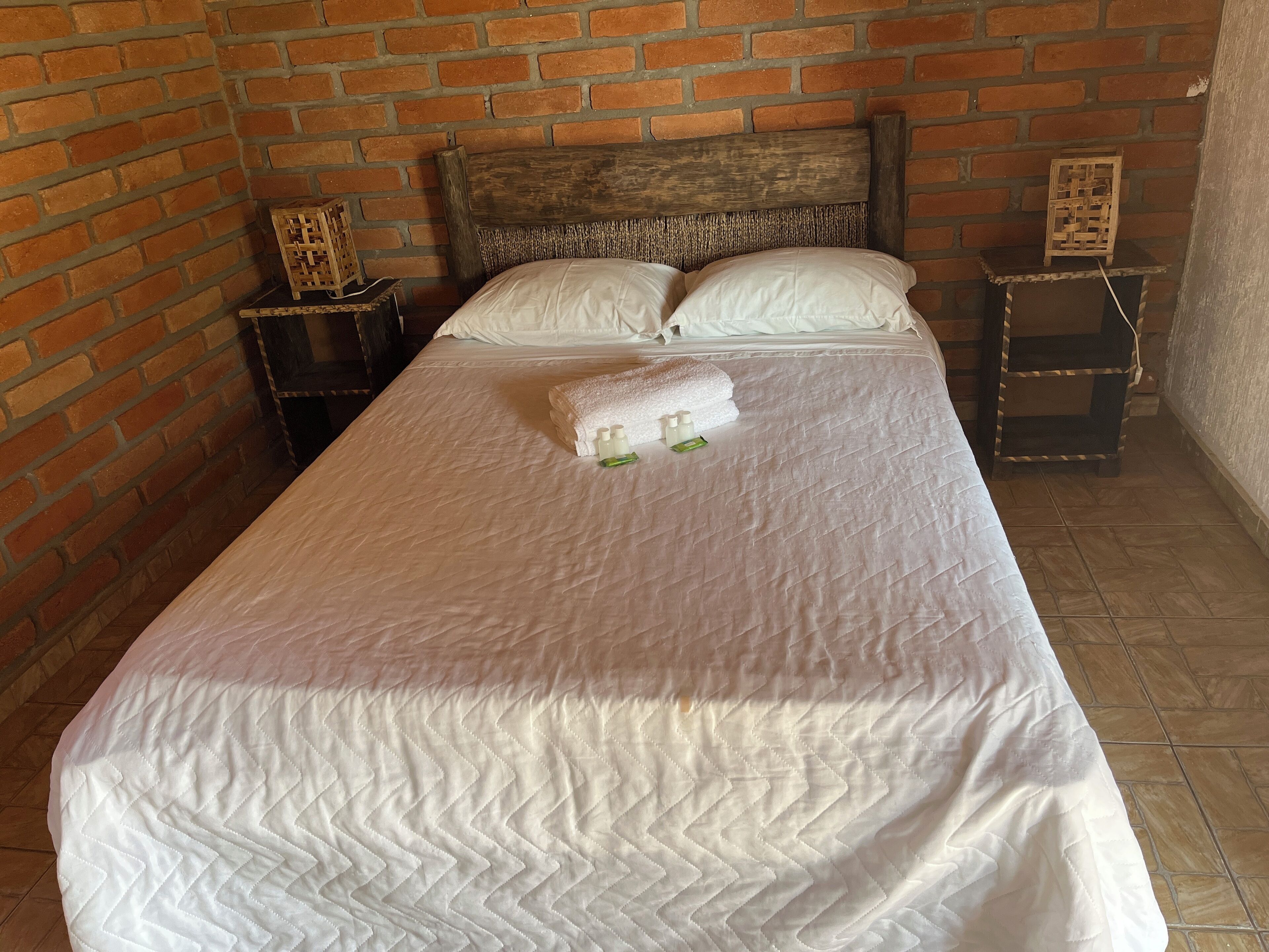 A neatly made bed with a white quilt, a wooden headboard, and two bedside tables with decorative items.