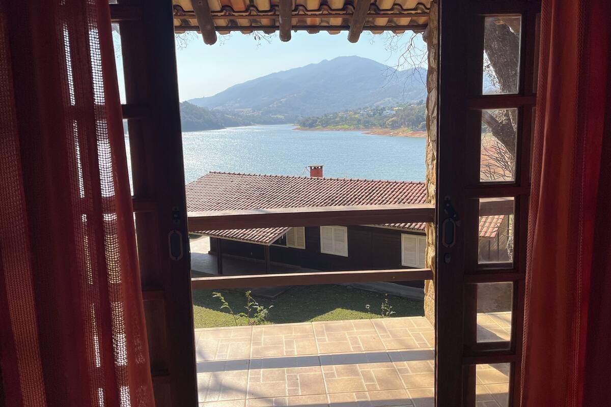 Uma porta aberta com vista para uma paisagem montanhosa e um corpo d'água.
