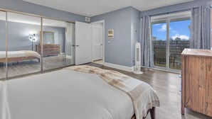 Un dormitorio con una cama grande, un armario, una puerta corrediza de vidrio a un balcón y un pequeño calentador.