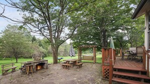 A patio area with stone flooring, wooden benches, a table, and a grill. - Pondside Retreat Near Narrowsburg & The Delaware River (Beach Lake)