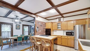 A kitchen with wooden cabinets, a central island with bar stools, a microwave, and a refrigerator. - Pondside Retreat Near Narrowsburg & The Delaware River (Beach Lake)