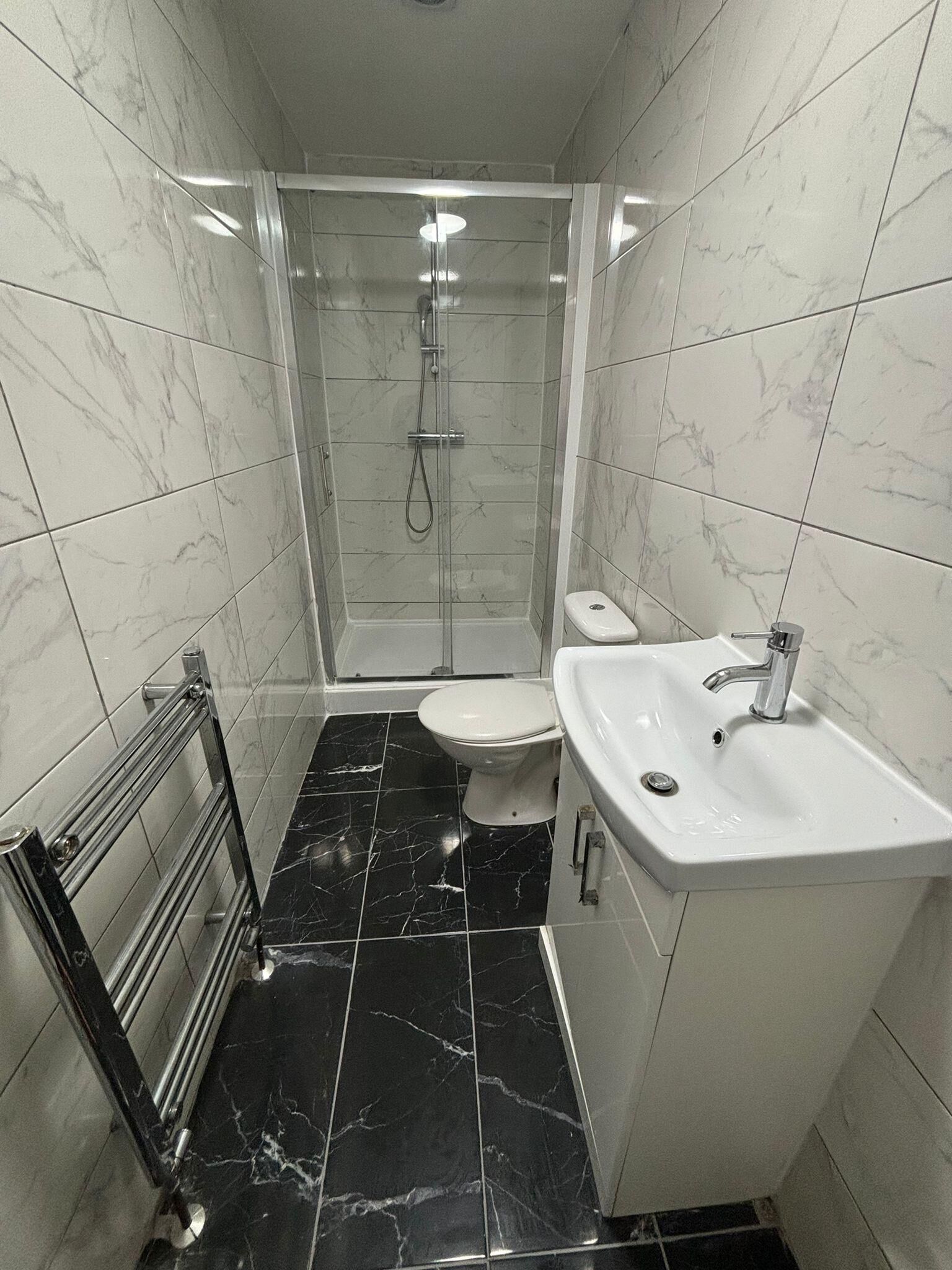 A bathroom with a shower, toilet, and sink.