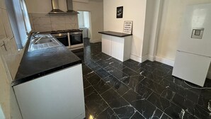 A modern kitchen with a black marble floor, white cabinetry, a built-in oven, and a stainless steel range hood. - Luxe Spacious 5-bed House in Liverpool (Liverpool)