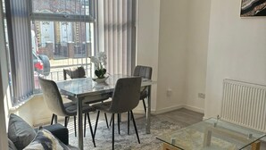 A modern living room with a glass coffee table, a sofa, and a dining area with chairs and a table. - Luxe Spacious 5-bed House in Liverpool (Liverpool)