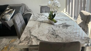 A modern living room with a marble dining table, grey sofa, and a potted orchid. - Luxe Spacious 5-bed House in Liverpool (Liverpool)