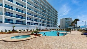 Un hotel moderno con un amplio área de piscina, numerosas tumbonas y una vista despejada del océano.