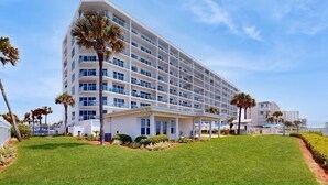 Un hotel de varios pisos con diseño moderno, que cuenta con balcones y un césped bien cuidado.