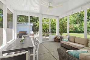 A covered patio with a table and chairs, a sofa, and a ceiling fan.