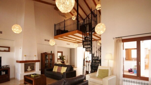 Amplia sala de estar con chimenea, televisor y escalera que conduce a un nivel superior.