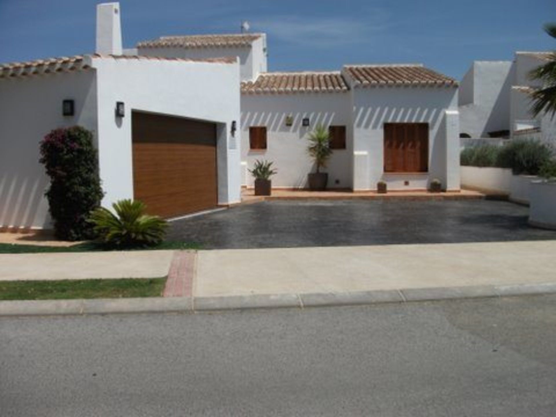 A modern two-story house with a tiled roof, a garage, and a paved driveway.