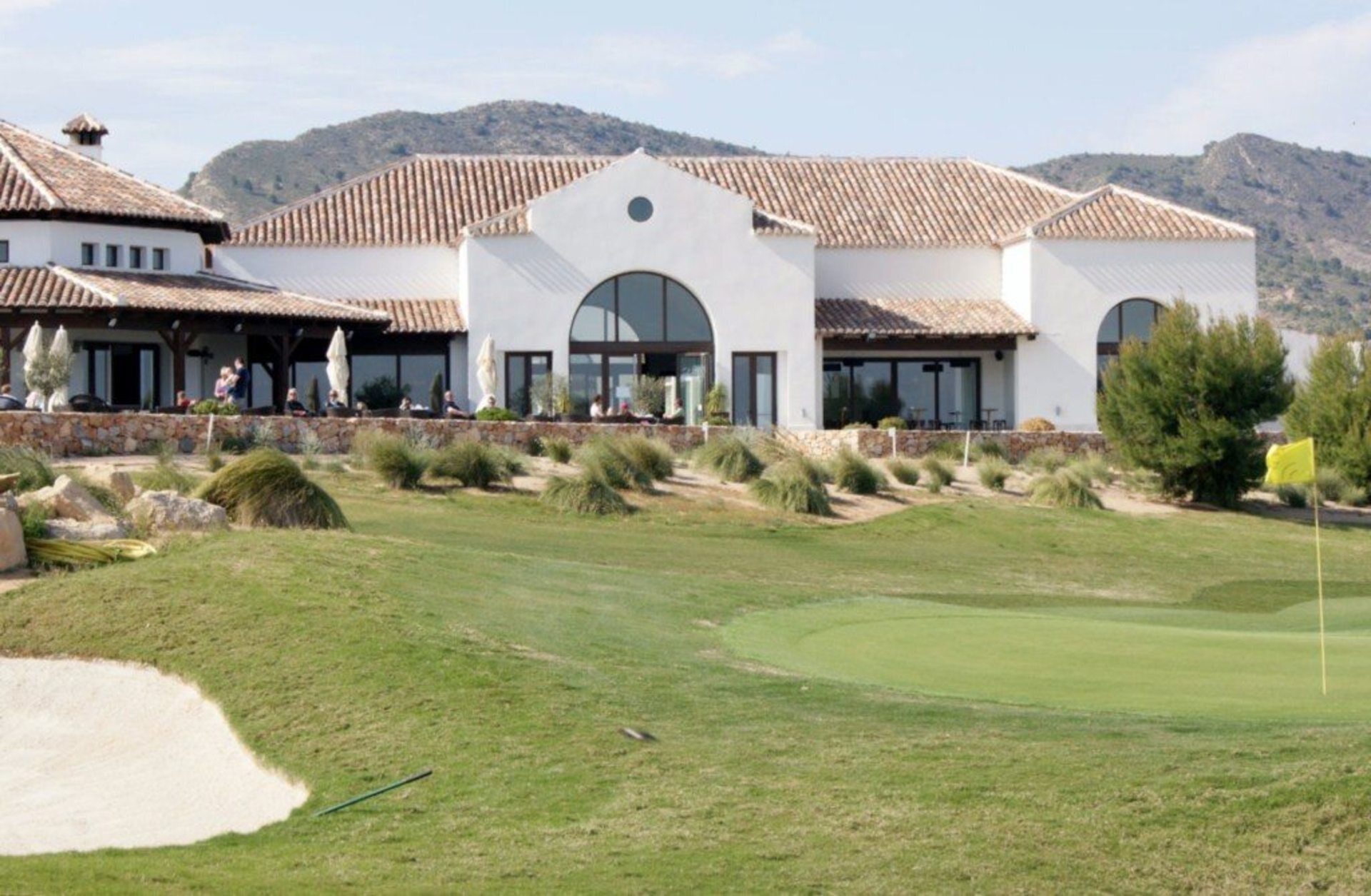 A golf course with a clubhouse featuring a modern design with large windows and a flat roof.