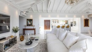 Ein geräumiges Wohnzimmer mit einem großen, weißen Sofa, einem Marmortisch und einer Kristallleuchter.