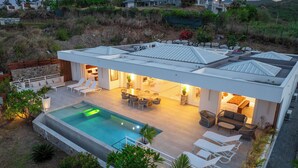 Ein modernes Haus mit Schwimmbad, Sitzgelegenheiten im Freien und einer Terrassenfläche.