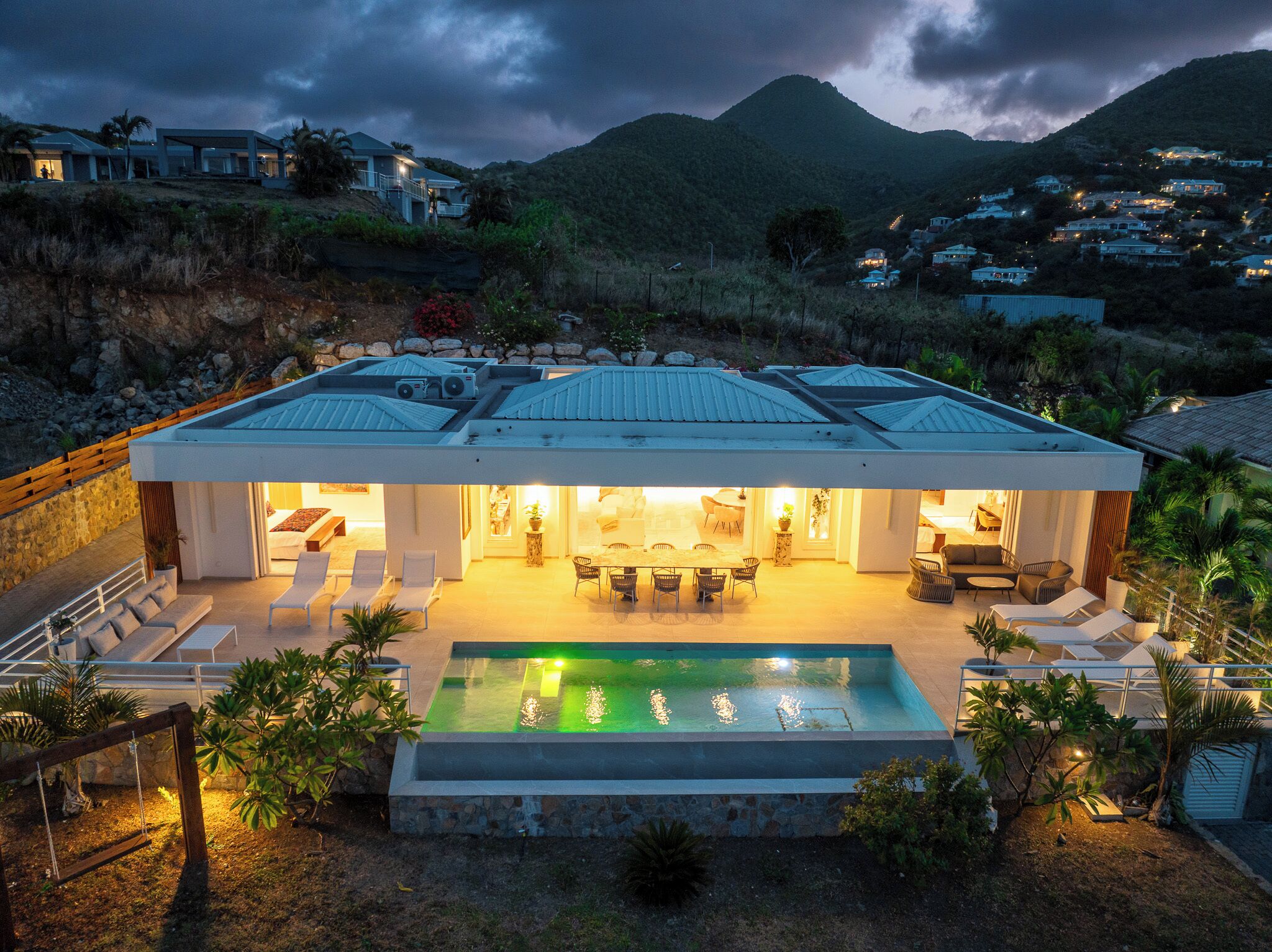 Une maison moderne dotée d’une piscine, d’un espace salon extérieur et offrant une vue sur les collines environnantes.