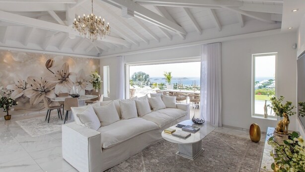 Ein geräumiges Wohnzimmer mit weißem Sofa, einem Couchtisch und Blick ins Freie.