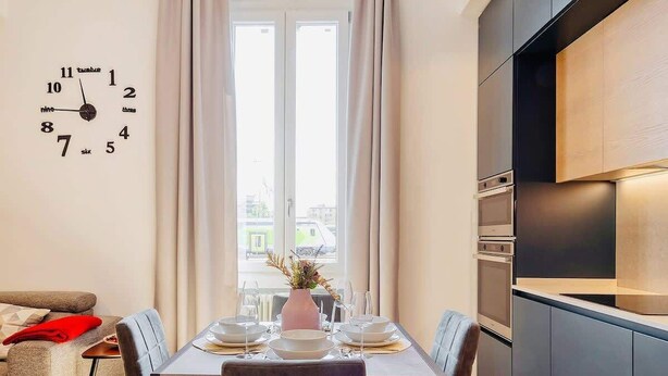 Una cocina moderna con comedor, un reloj en la pared y vistas al exterior.